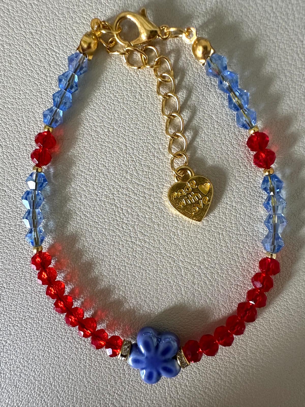 ADDISON handmade bracelet with blue and red crystal beads, golden rhinestones, and flower-shaped ceramic bead on gold-plated chain
