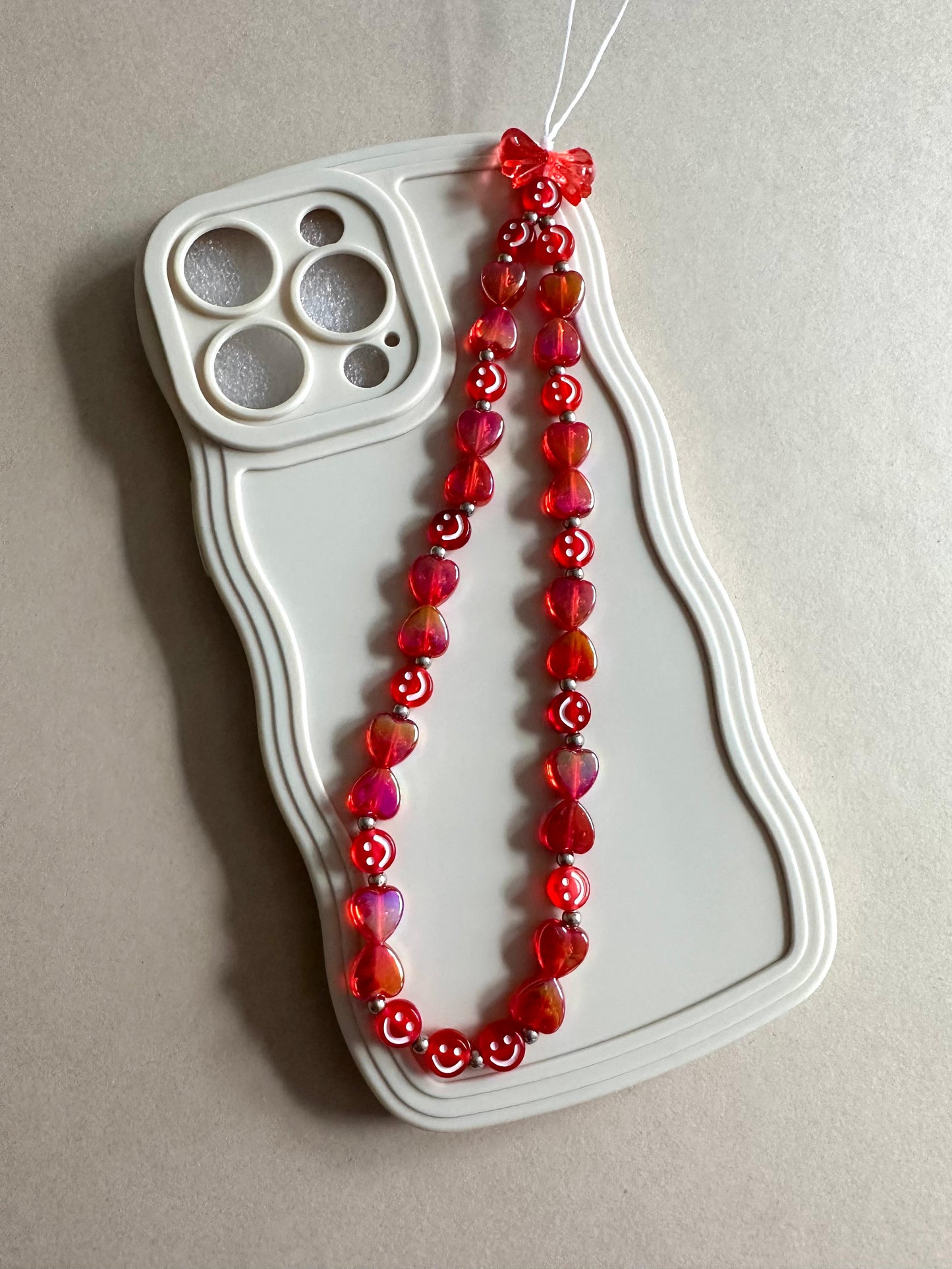Handmade red love vibes phone charm with beads attached to a smartphone