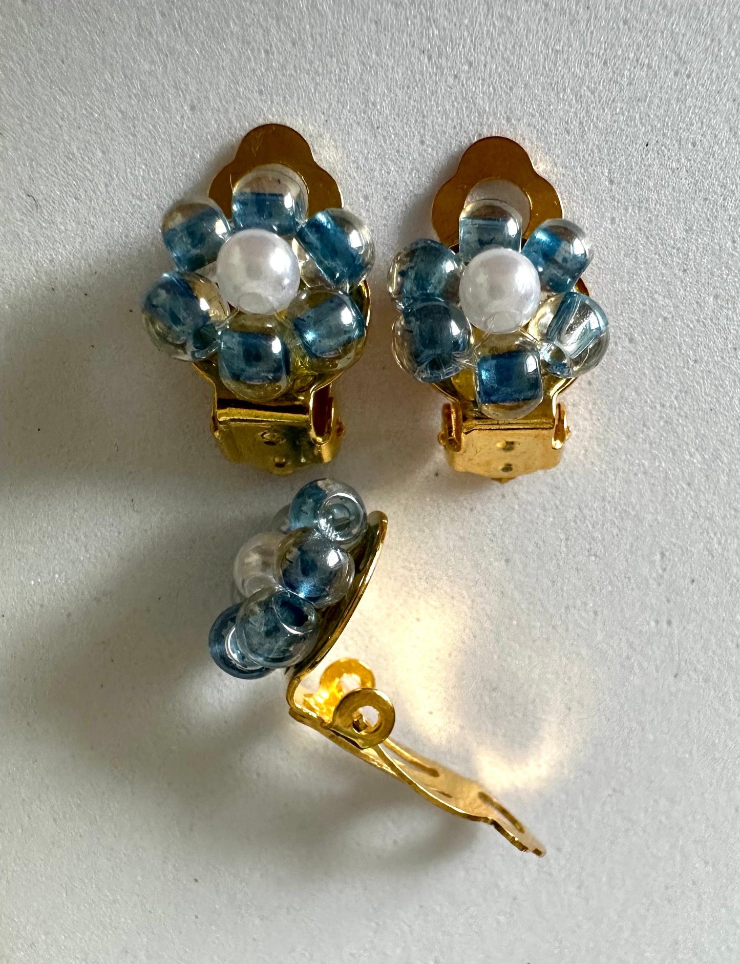 Pearl Blossom clip-on earrings with white petals and blue center, handmade floral design for non-pierced ears