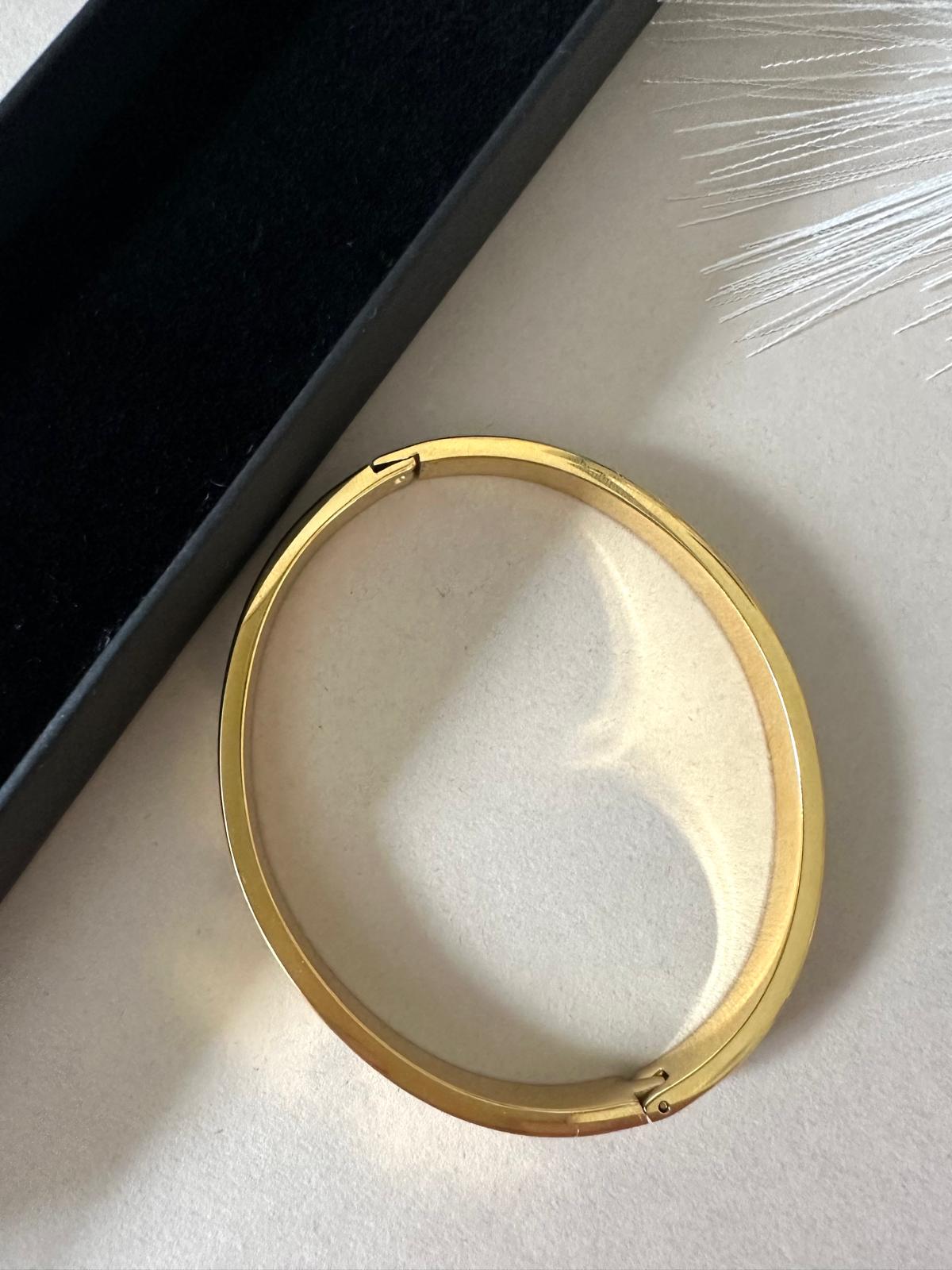 Gold polished bangle bracelet with crystal accents, minimalist and elegant design