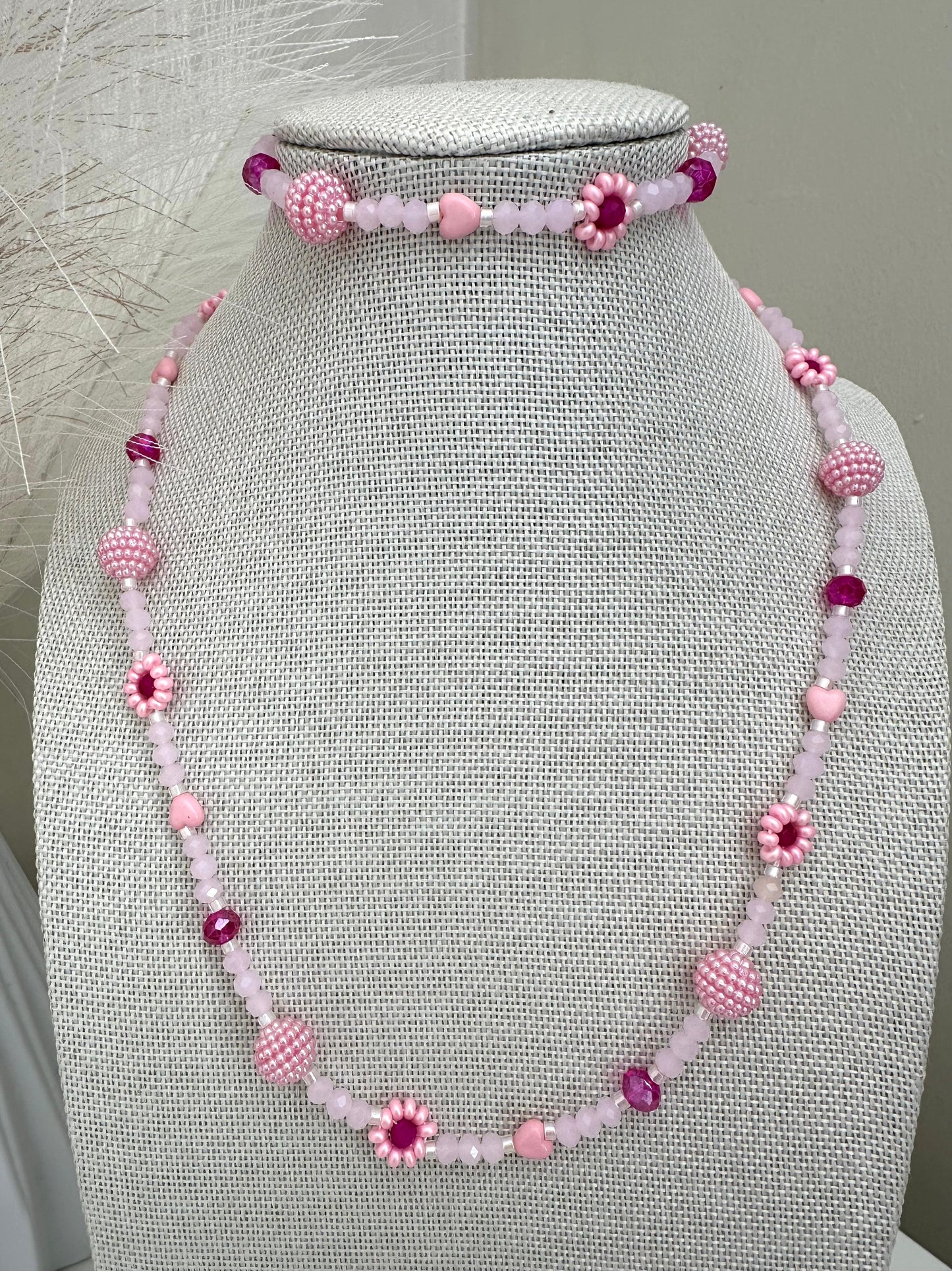 Blush tone handmade necklace with pink and fuchsia glass beads, faux pearls, and floral details on stainless steel chain