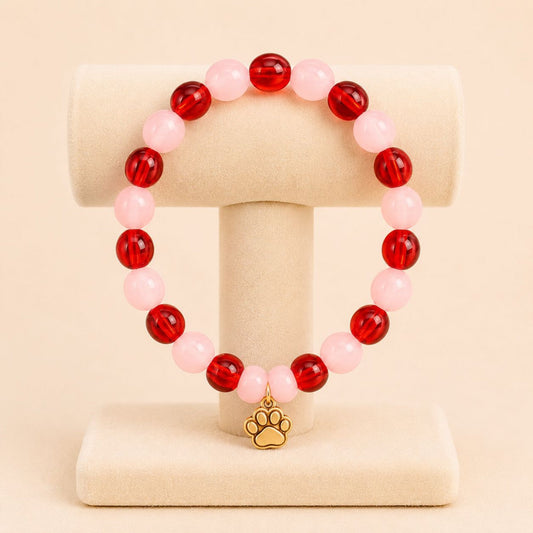 Golden furry friend stretch bracelet with red and pink beads and golden paw print charm