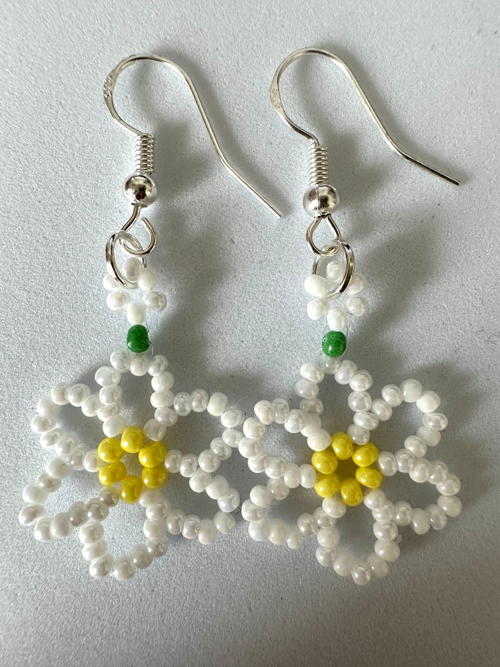 Close-up of DAISY BLOOM silver handmade floral earrings with white and sky blue beads on sterling silver hooks