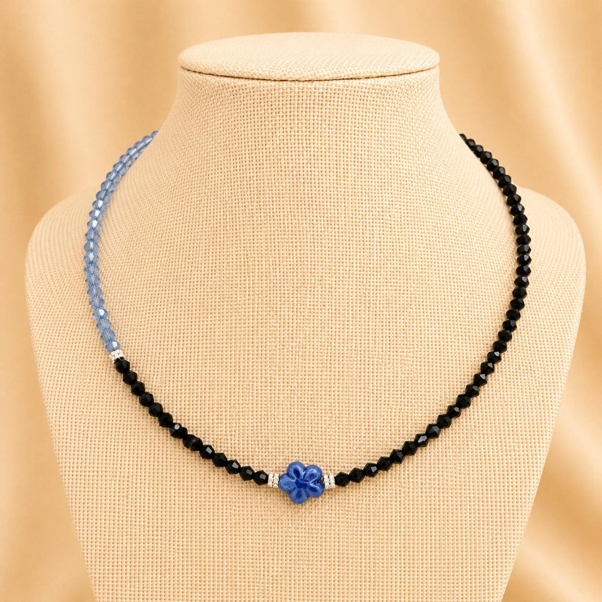 Handmade AUBREE necklace with blue and black crystal beads, silver rhinestone spacers, and blue flower ceramic bead on stainless steel chain