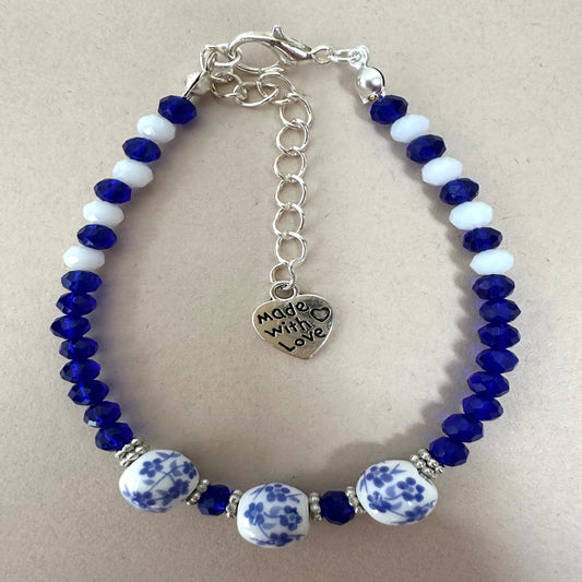 Handmade BLUVERDANT BLOSSOM bracelet with indigo and white glass beads, silver spacers, ceramic beads, and adjustable stainless steel chain