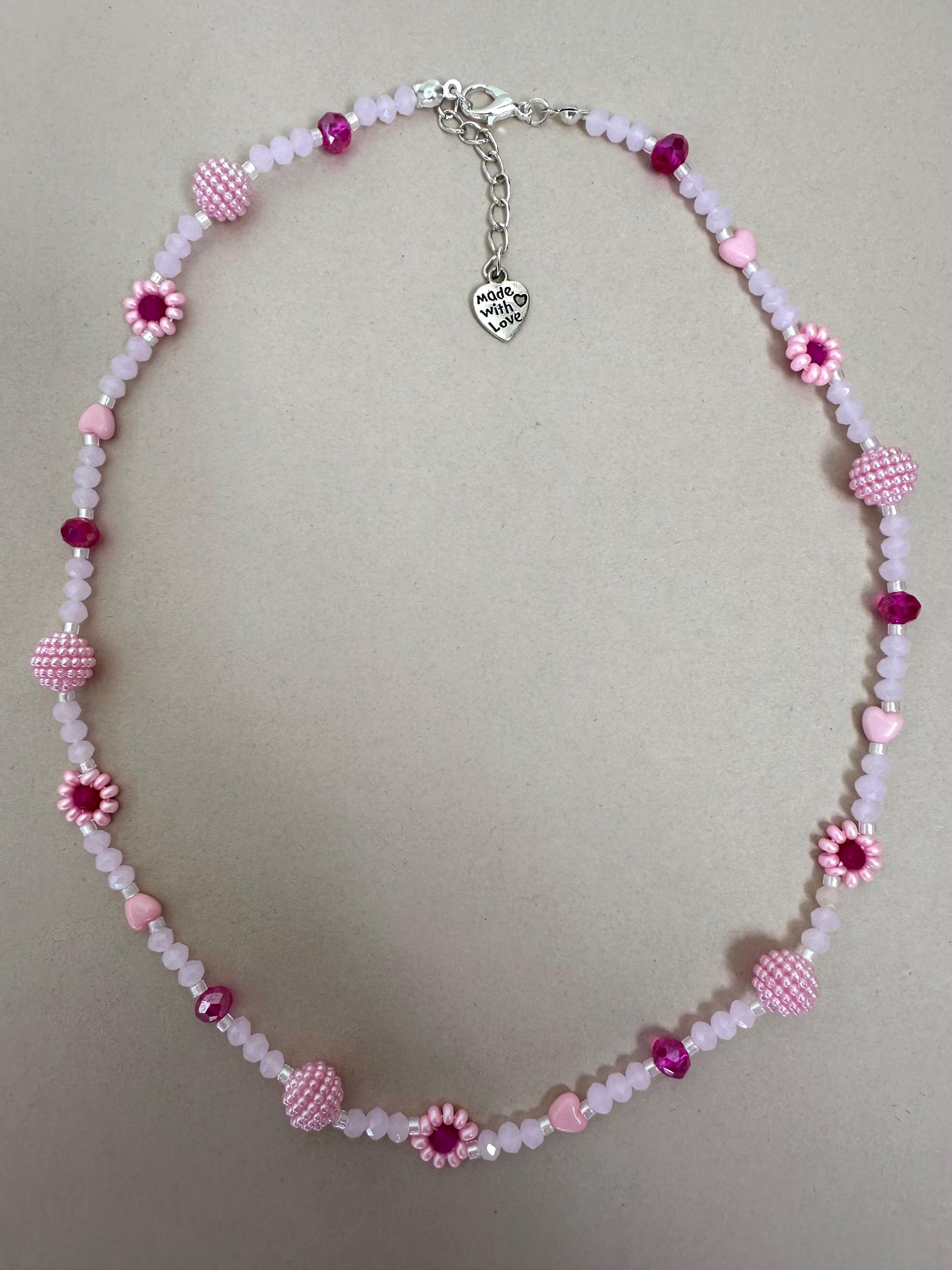 Blush tone handmade necklace with pink and fuchsia glass beads, faux pearls, floral details, and stainless steel extender chain