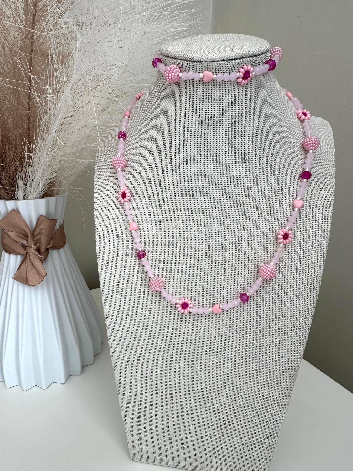 Blush tone handmade necklace with pink and fuchsia glass beads, faux pearls, and floral details on stainless steel chain