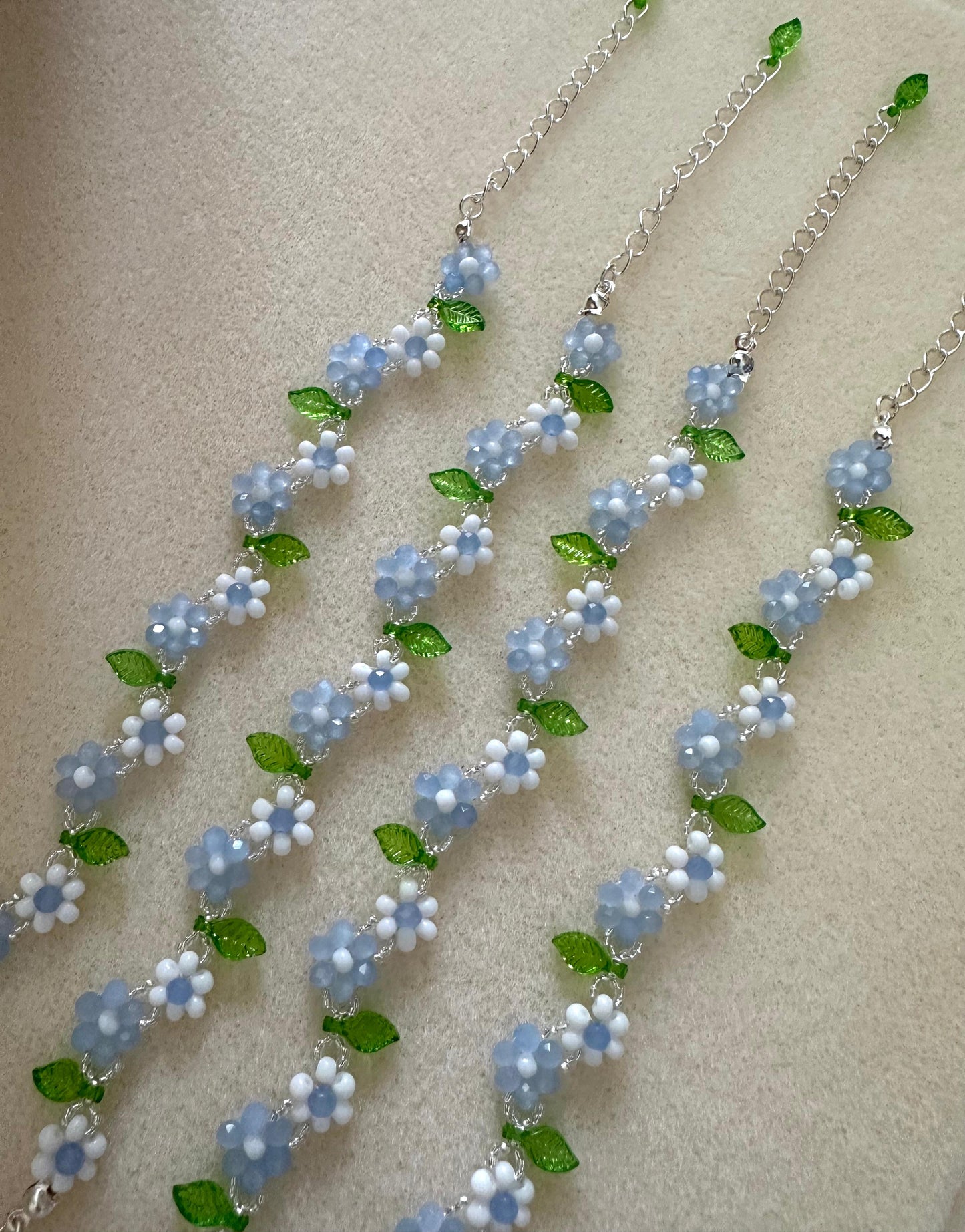 Handmade EVERYDAY FLORAL bracelet with white, blue, silver, and green beads on nylon string