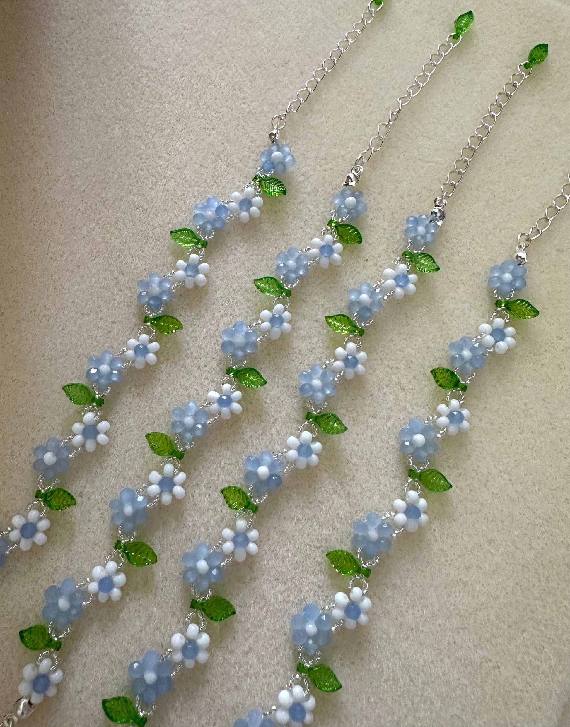 Handmade EVERYDAY FLORAL bracelet with white, blue, silver, and green beads on nylon string