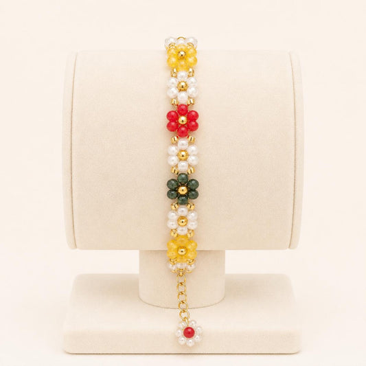 Colorful flower handmade bracelet with white, green, red, and yellow beads and gold accents on a nylon string
