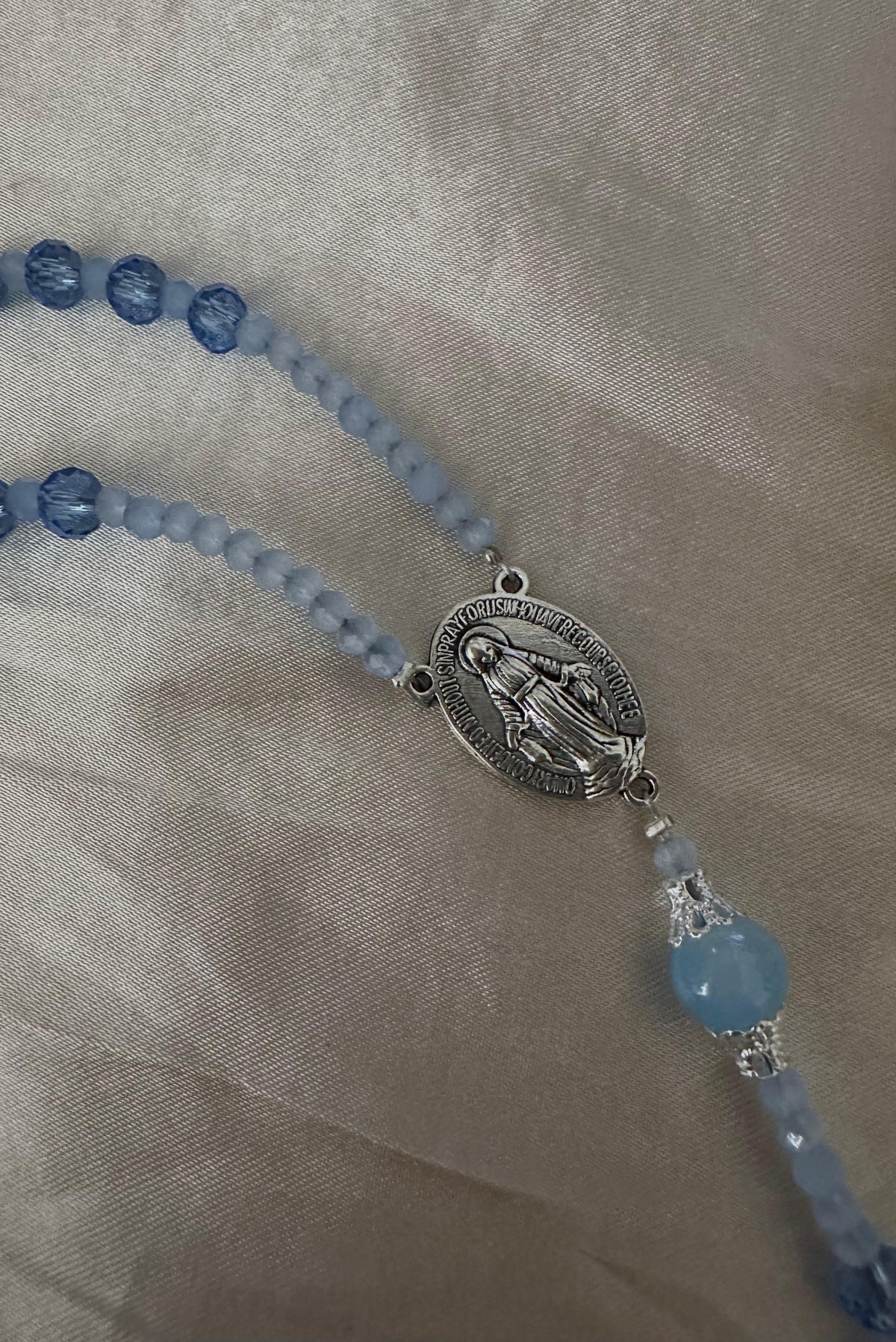 Blue Serenity Handmade Rosary with faceted blue and pale blue glass beads, silver-tone Virgin Mary centerpiece and filigree accents