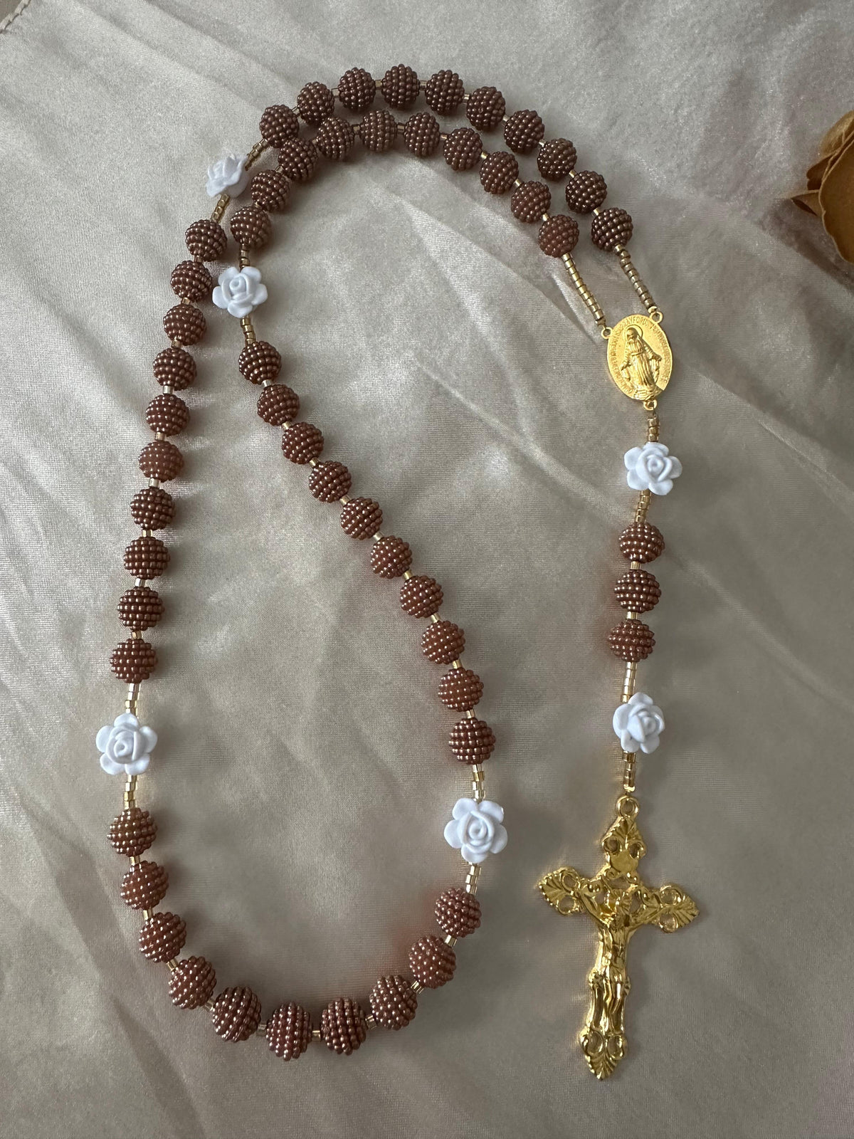 Cocoa Grace Handmade Rosary with textured brown beads, white rose-shaped beads, gold-tone details, and ornate crucifix