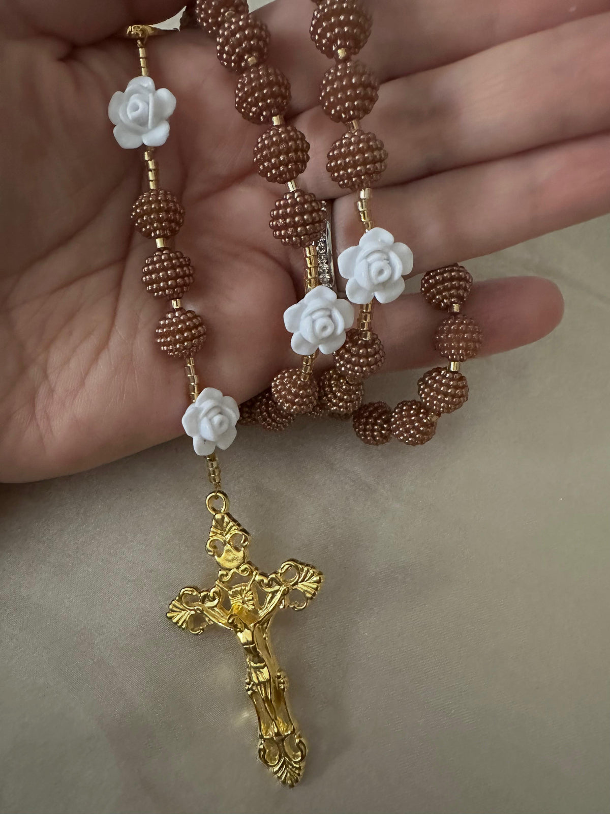 Cocoa Grace Handmade Rosary with textured brown beads, white rose-shaped beads, and an ornate gold-tone crucifix.