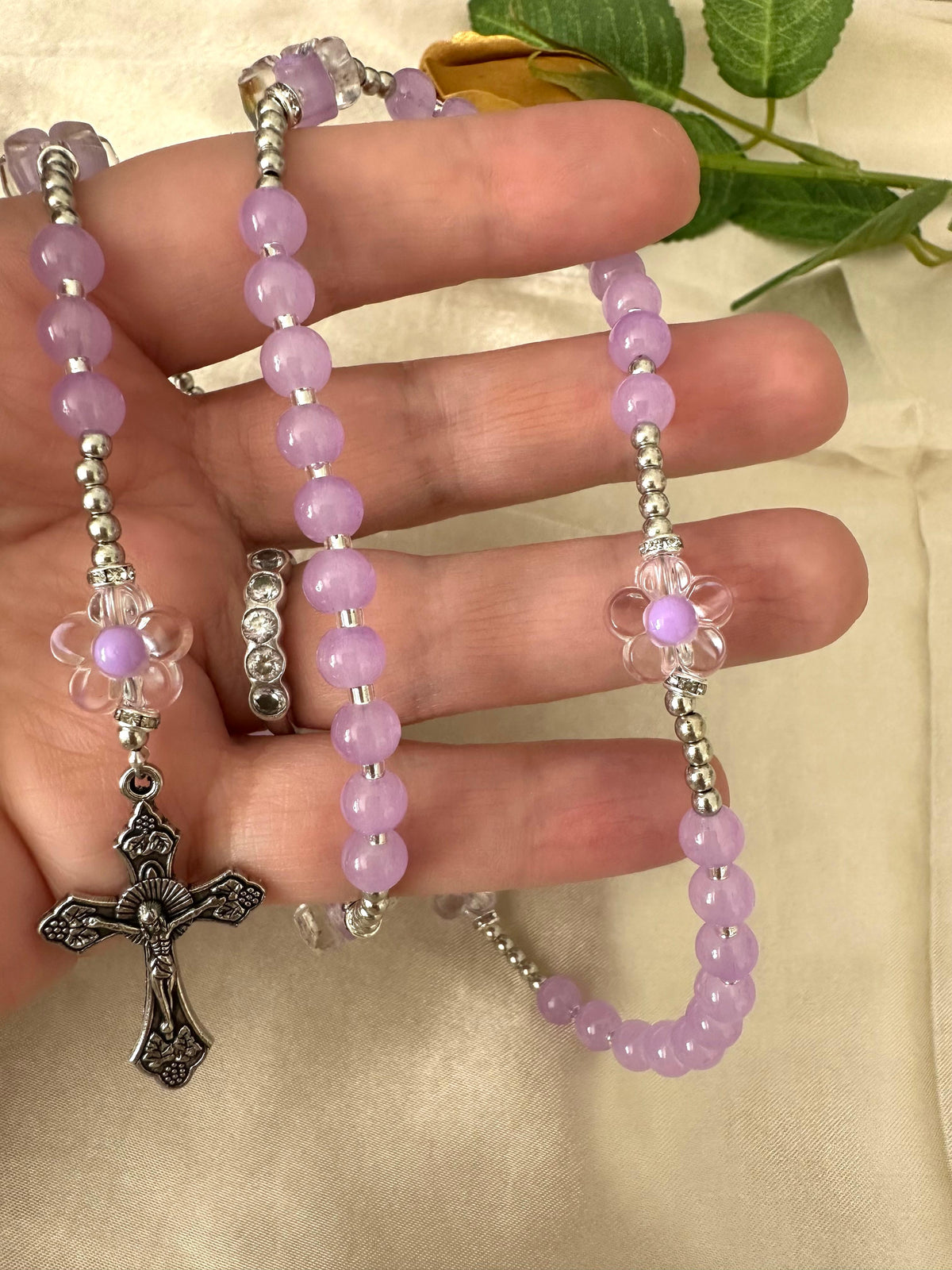 Lilac Blossom Handmade Rosary featuring lilac glass beads, silver-tone spacers with rhinestones, flower accents, and a silver crucifix.