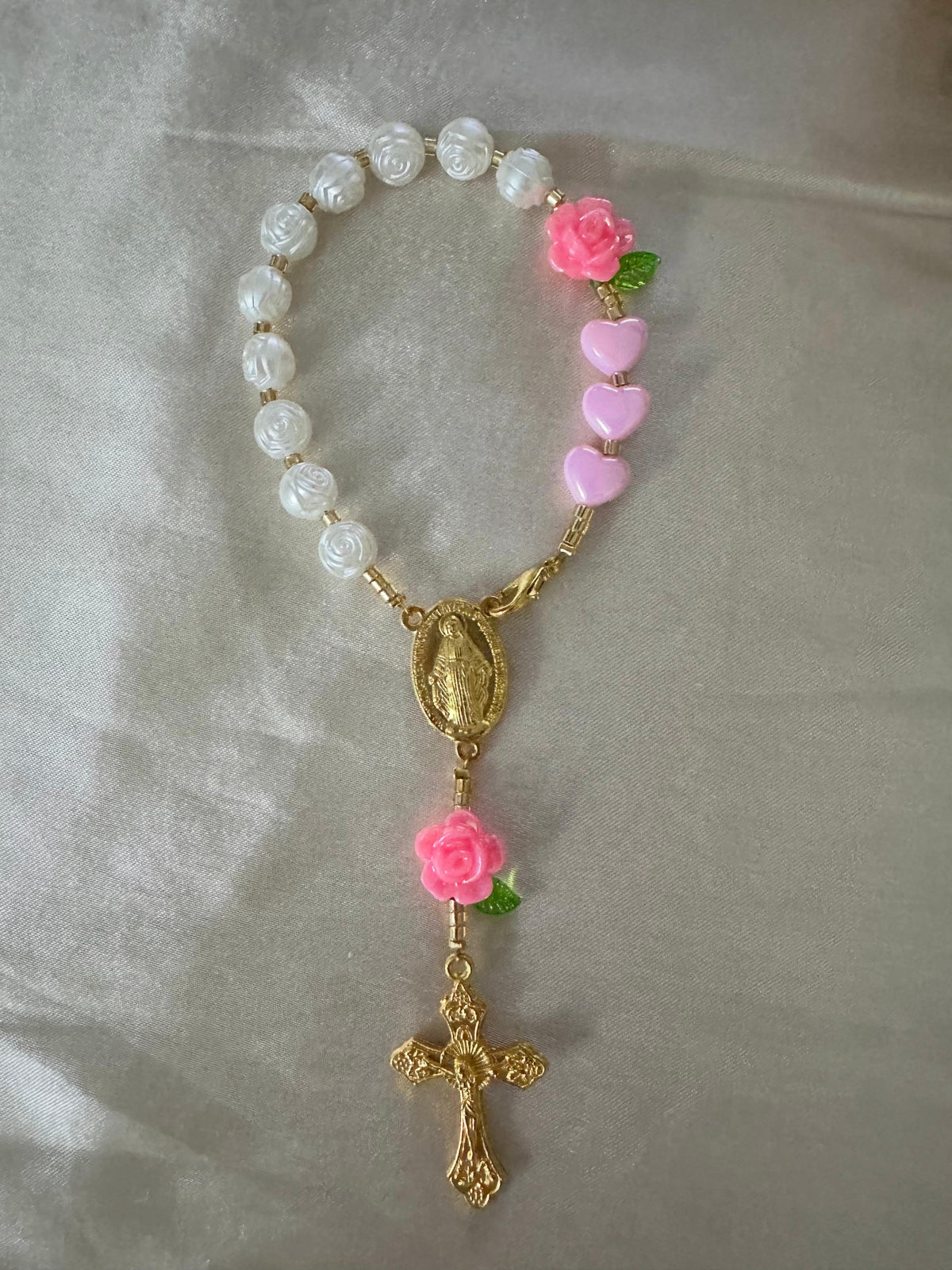 Pink Rose Mini Rosary with ivory rose-shaped beads, pink hearts and flowers, green leaves, and gold-tone centerpiece and crucifix.